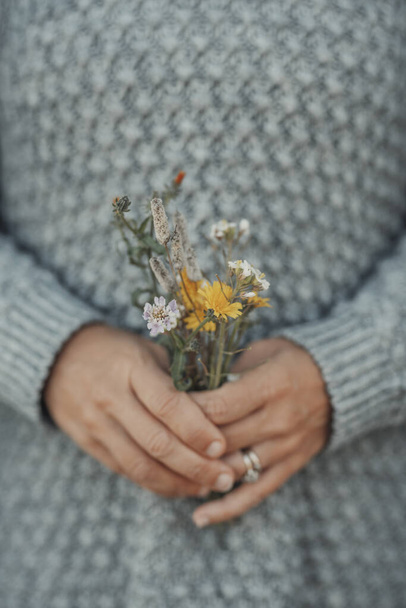 Romantisch beeld van mensen en natuur met handen die natuurlijke bloemen van het veld houden. De lente komt eraan. Concept van gemakkelijke levensstijl en natuurlijk leven. Aardse dag. Milieu en duurzame close-up - Foto, afbeelding
