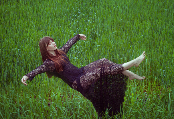 Женщина парит в воздухе, лежа, как во сне. Она колеблется над зеленым полем травы. Она левитирует на улице.. - Фото, изображение