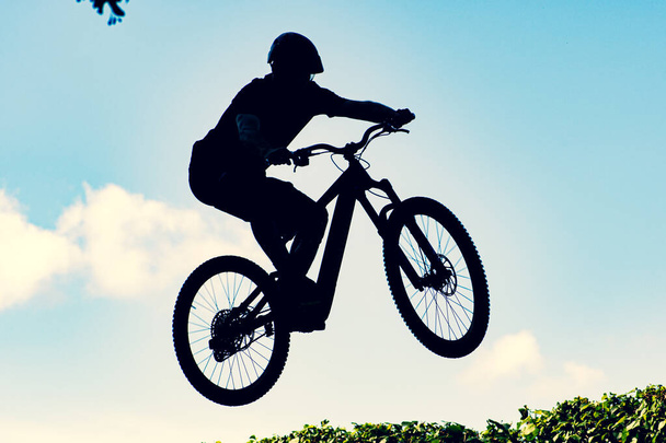 Silhouette of a biker performing an extreme dirty jump with a bmx bike against the sky - Photo, Image