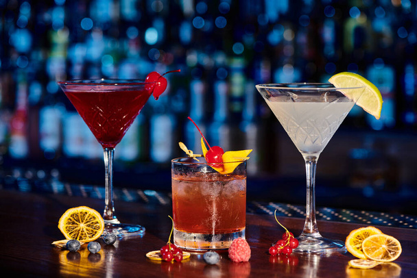 освежающий мартини, негрони и космополит на барной стойке со свежими ягодами, концепция - Фото, изображение