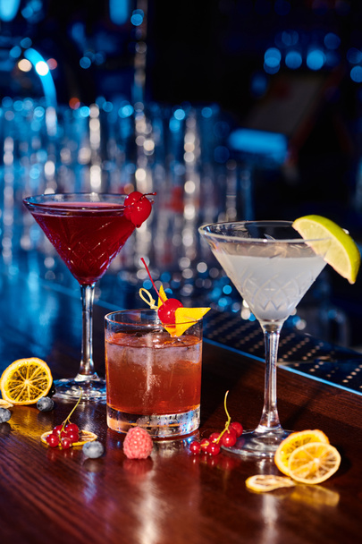 изысканные коктейли с гарниром на барной стойке со свежими ягодами, концепция - Фото, изображение
