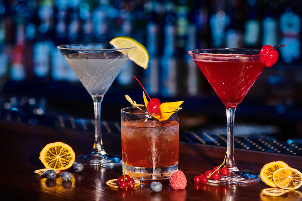 Durstlöschende Cocktails mit frischen Dekorationen auf Theke mit Barkulisse, Konzept - Foto, Bild