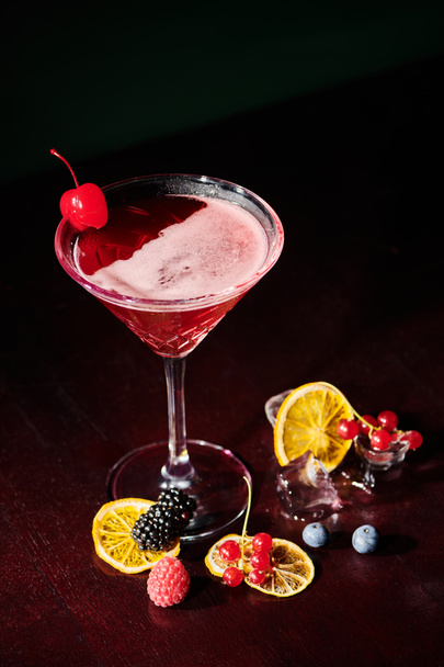 ovocný elegantní kosmopolitní koktejl se studenými ovocnými kostkami ledu na černém pozadí, koncept - Fotografie, Obrázek