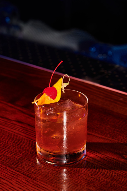 ледяной стакан из негрони, украшенный вишней на барной стойке, концепция - Фото, изображение
