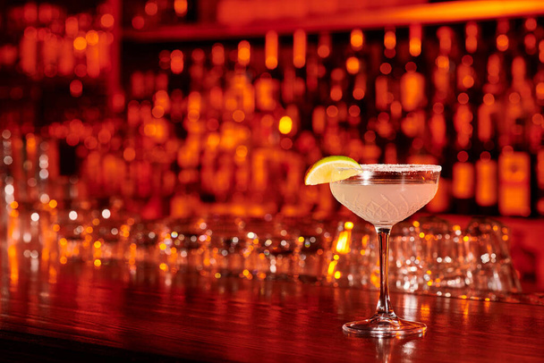 изысканный стакан маргариты, украшенный ломтиком лайма на фоне бара, концепция - Фото, изображение