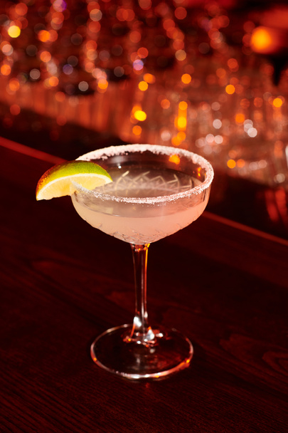 освежающий ледяной напиток маргариты, украшенный ломтиком лайма на барной стойке, концепция - Фото, изображение