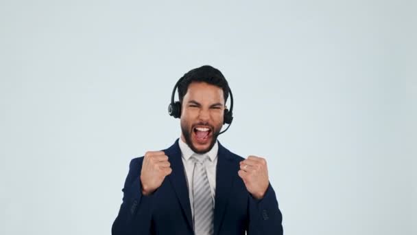 Telemarketing, face and man with celebration, promotion and call center on a white studio background. Portrait, happy person and consultant with headphones, tech support and winning with achievement. - Footage, Video