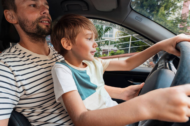 Padre enseñando a su hijo a conducir en su regazo - Foto, imagen