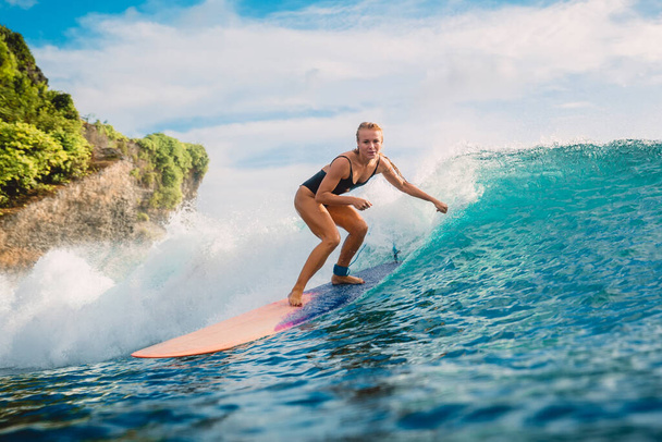Surf meisje op longboard. Aantrekkelijke surfer vrouw en blauwe golf - Foto, afbeelding