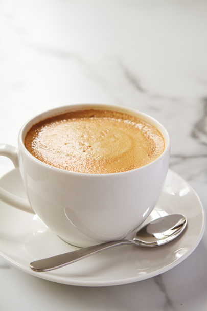 Cappucino ou café com leite com leite em xícara branca e pires em um café
 - Foto, Imagem