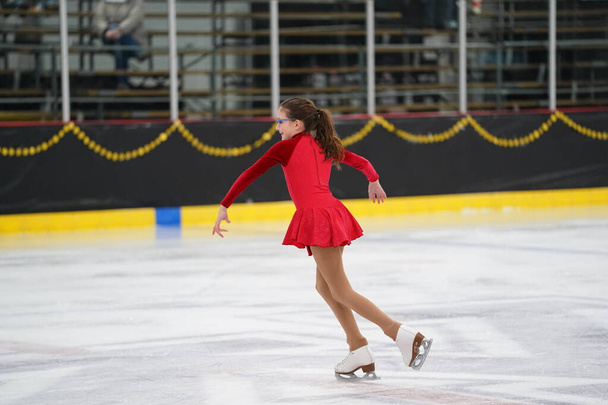 Феллини, штат Висконсин, США - 26 февраля 2021 года: взрослая женщина в красивом красном платье приняла участие в соревнованиях по конькобежному спорту на зимних играх штата Барсук - Фото, изображение
