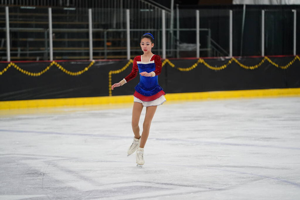 Mosinee, Wisconsin USA - 26 februari 2021: Jonge volwassen vrouw in een prachtige blauwe jurk nam deel aan dassenstaat winterspelen schaatsen competitie. - Foto, afbeelding