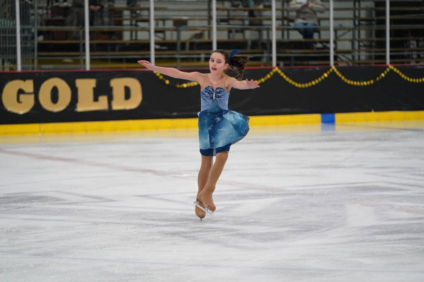 Мосідін, штат Вісконсин США 26 лютого 2021 року: Молода доросла жінка в красивій блакитній сукні взяла участь у змаганнях з зимового катання на ковзанах. - Фото, зображення