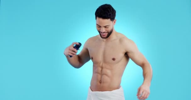 Body, spray and man with deodorant and perfume for cosmetic, hygiene and clean smell on blue background in studio. Antiperspirant, product and model with beauty, scent and wellness in self care. - Footage, Video