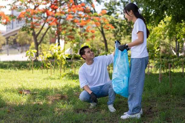 Happy young Asian students diverse volunteers with garbage bags cleaning area in the park, The concept of environmental conservation on world environment day, recycling, charity for sustainability. - Φωτογραφία, εικόνα