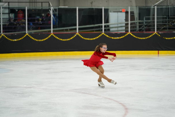 Mosinee, Wisconsin EUA - 26 de fevereiro de 2021: Mulher adulta em um lindo vestido vermelho participou da competição de patinação no gelo de jogos de inverno do estado de texugo - Foto, Imagem