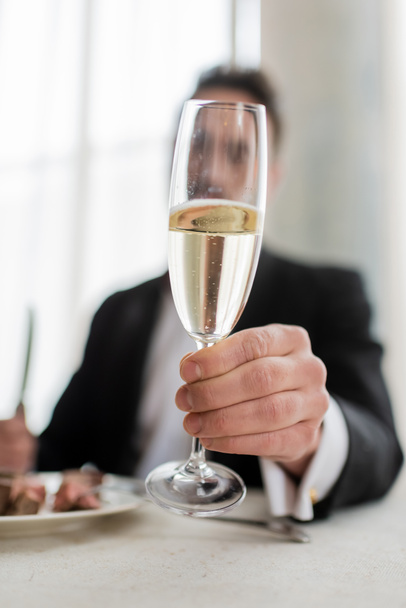 夕食を食べながらシャンパンのグラスを保持するスーツの紳士の見た目, クローズアップショット - 写真・画像