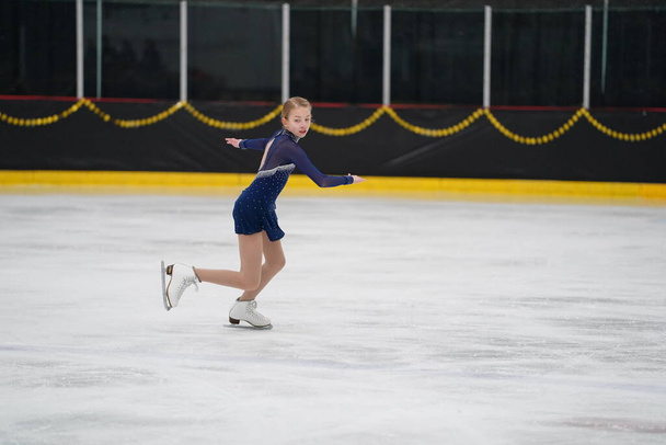 Mosinee, Wisconsin, EE.UU. - 26 de febrero de 2021: Mujer adulta con un hermoso vestido azul participó en la competencia de patinaje sobre hielo de los juegos de invierno de Badger State. - Foto, Imagen
