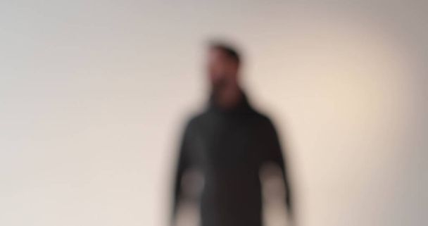 En el estudio se filmó un hermoso material artístico de un hombre con una chaqueta oscura. El objeto principal entra en foco y se desenfoca suavemente. - Foto, Imagen