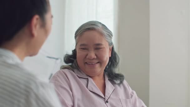Вид на плече дочки, яка відвідує хвору матір з інвалідністю у лікарні та розмовляє - Кадри, відео