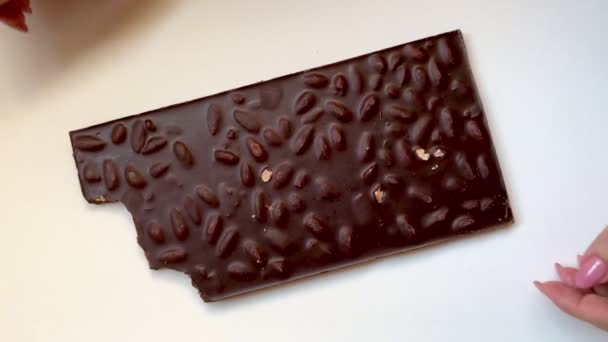 Mãos de mulher quebrando barras de chocolate escuro no fundo branco. Visão superior saboroso porca lanches vídeo. Imagens 4k de alta qualidade - Filmagem, Vídeo