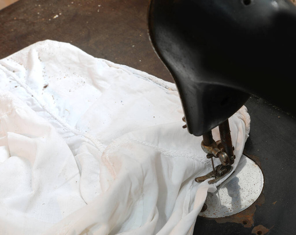 дуже стара швейна машина з голкою і ниткою для ремонту білої сорочки - Фото, зображення