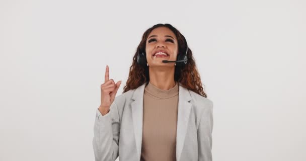 Call center, woman and pointing up with headset in studio for crm or advice and advertising. Portrait of customer service consultant with announcement, contact us and support on a white background. - Footage, Video