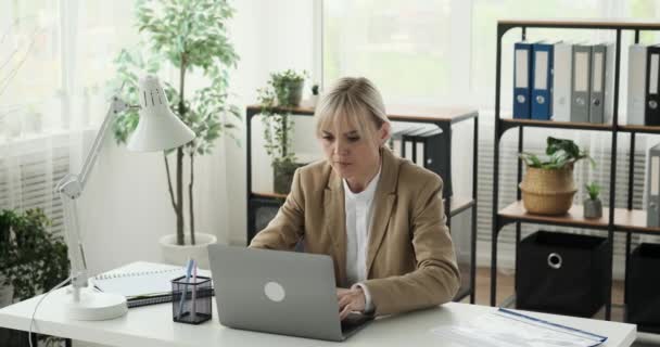 Een boze kantoormedewerker wordt gefrustreerd en van streek gezien, waardoor ze haar laptop abrupt sluit. Haar gezichtsuitdrukkingen drukken duidelijk negatieve emoties uit als reactie op een teleurstellende. - Video