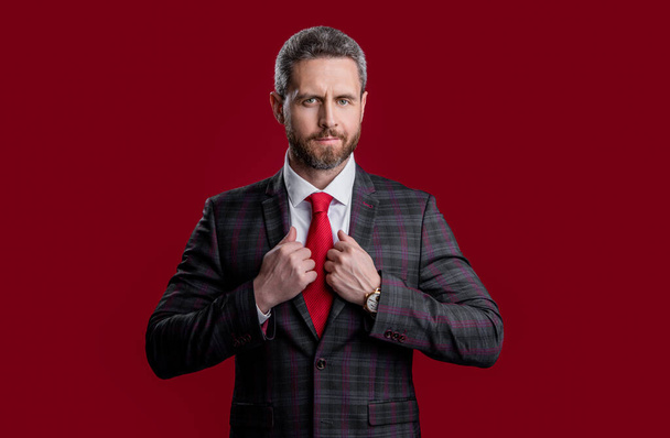 confident business man wearing formalwear in studio. photo of business man wear formalwear. business man in formalwear suit. business man in formalwear isolated on red background. - Photo, image