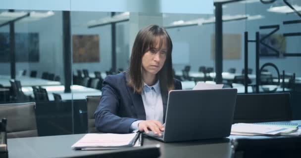 W środowisku biurowym, biała kobieta jest zanurzona w swojej pracy z papierami. Jej skupienie uwagi na dokumentach przed nią odzwierciedla jej zaangażowanie na rzecz dokładności. - Materiał filmowy, wideo