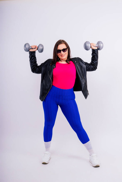 Dambıllarla egzersiz yapan tombul bir kadın. Spor motivasyonu ve sağlıklı yaşam tarzı - Fotoğraf, Görsel