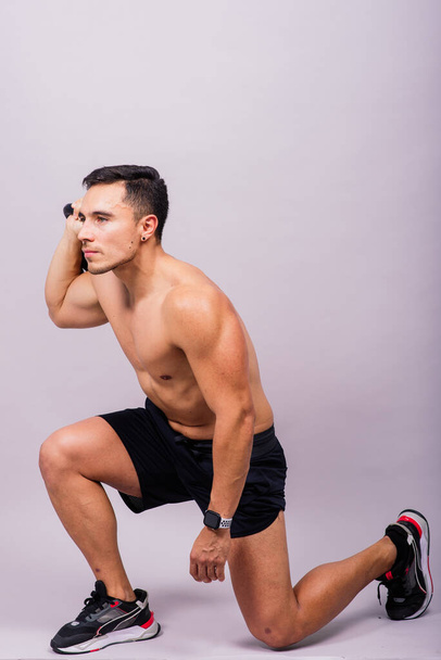 Corpo inteiro de homem musculoso exercitando com halteres em um fundo branco e escuro - Foto, Imagem