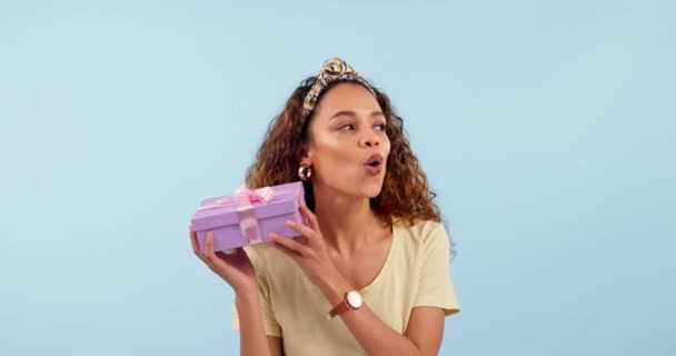Excited, woman shake present and box in studio isolated on a blue background mockup space. Portrait, happy person guessing gift package and curious at party, birthday celebration and holiday prize. - Footage, Video