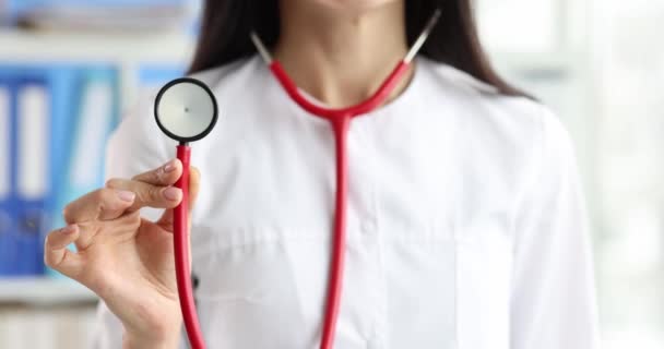 Vrouwelijke arts in uniform houdt stethoscoop om de patiënt te onderzoeken in kliniek kantoor. Professionele kleding voor expert en consult slow motion - Video