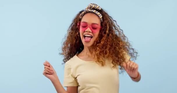 Happy, dancing and young woman in a studio with funky, cool and stylish sunglasses listening to music. Smile, excited and young female model from Colombia moving and having fun by white background - Footage, Video