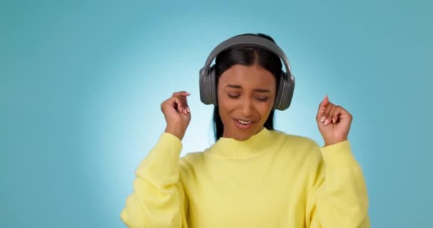 Tánc, boldog nő és zenei fejhallgató a stúdióban ünnepelni a szabadság, párt vagy hallás audio dal kék háttérrel. Izgalmas indiai modell hallgatja multimédia, hang vagy rádió előfizetés. - Felvétel, videó