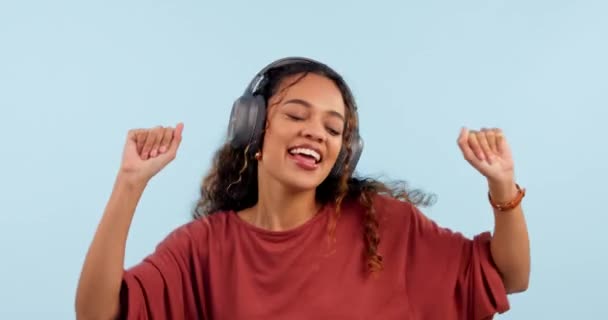 Woman, dancing and headphones for music in studio, listening and moving to beat by blue background. Dancer girl, audio tech and streaming subscription with freedom, energy and hearing with sound. - Footage, Video