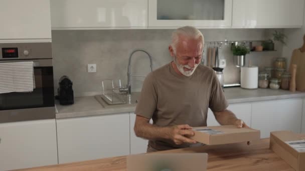 Ένας ανώτερος καυκάσιος άνδρας στο σπίτι hold cardbox πακέτο παραδοθεί δώρο ή να διατάξει αργή κίνηση - Πλάνα, βίντεο