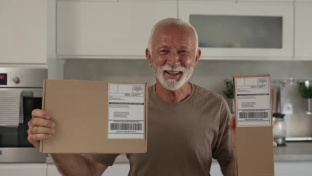 Un hombre caucásico senior en casa sostiene el paquete de la caja de cartón entregado regalo o pedido en cámara lenta - Metraje, vídeo