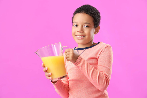Kis afro-amerikai fiú egy kancsó friss citruslé lila háttér - Fotó, kép