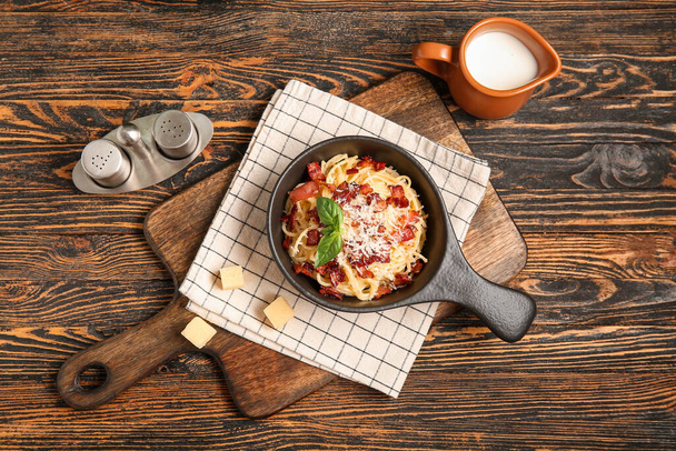 Braadpan met lekkere pasta carbonara op houten ondergrond - Foto, afbeelding
