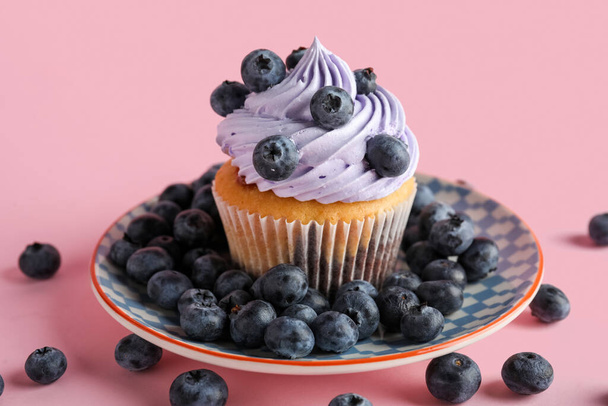 Lemez ízletes cupcake áfonyával rózsaszín alapon - Fotó, kép