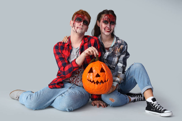 zombie spaventosi con zucca di Halloween su sfondo grigio - Foto, immagini