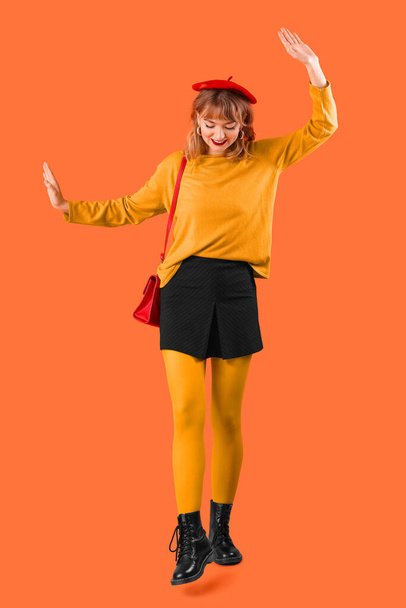 オレンジ色の背景に秋の服でスタイリッシュな若い女性 - 写真・画像