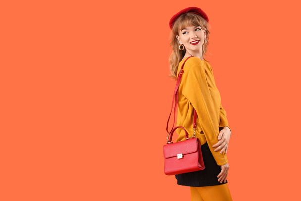 Stilvolle junge Frau in Herbstkleidung auf orangefarbenem Hintergrund - Foto, Bild