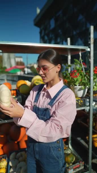 Una agricultora está mostrando una variedad blanca de calabaza que está vendiendo en el mercado. Imágenes de alta calidad 4k - Imágenes, Vídeo