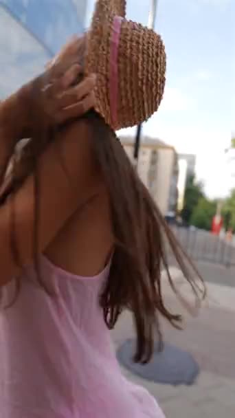 Egy elbűvölő, kamerás fiatal hölgy kalapban élvezi a sétát a város utcáin. Kiváló minőségű 4k felvételek - Felvétel, videó