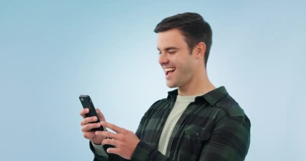 Winner, fist and happy man with phone in studio for wow, news or opportunity in blue background. Smartphone, app and male model with notification, feedback or review, email or competition results. - Footage, Video