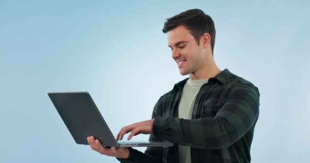 Laptop, szczęśliwy i mężczyzna w studiu, pisząc na maszynie do badań nad wolnym strzelcem z technologią, uśmiechem, kreatywną karierą i młodym męskim freelancerem z Kanady, pracującym nad copywritingiem według niebieskiego tła - Materiał filmowy, wideo