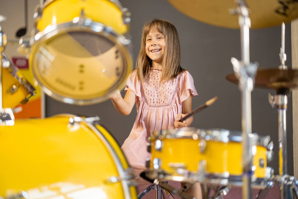 girl playing on a real drums, having fun while visiting a science museum - Foto, Imagen
